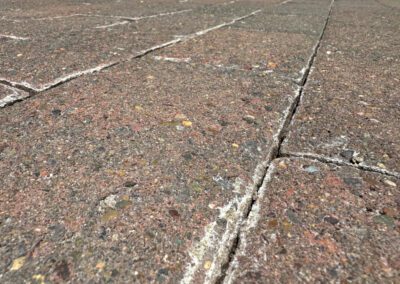 Close-up of a weathered brick pavement with visible cracks and seams.